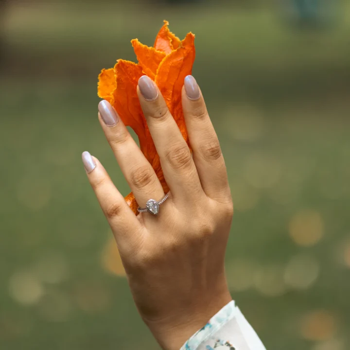 Ongles en amande tenant une fleur orange