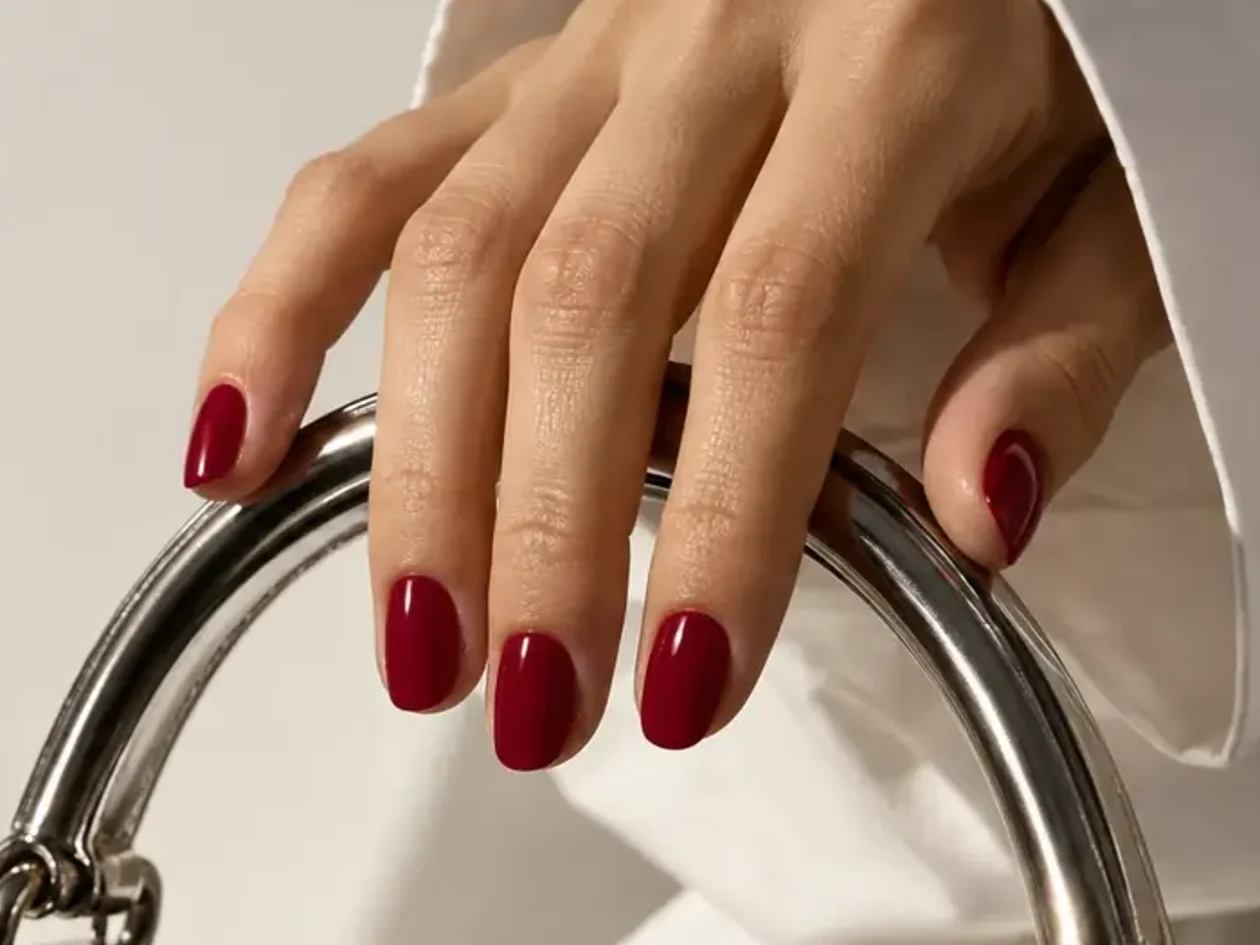 Ongles bordeaux posés sur une anse chromée