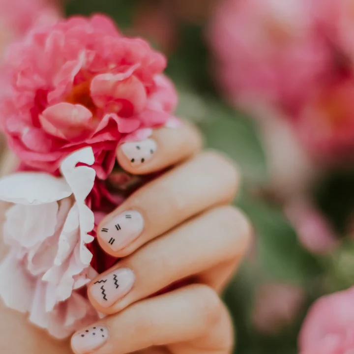 Ongles nude à petits motifs, main tenant des roses