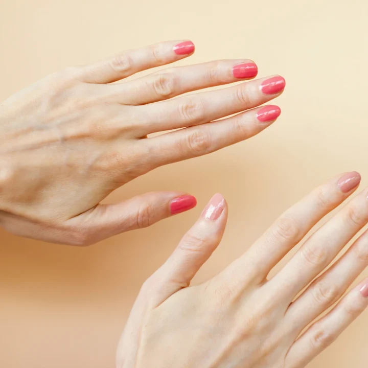 Ongles aux tons pastel corail sur fond crème