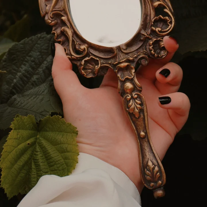 Ongles sombres tenant un miroir ancien
