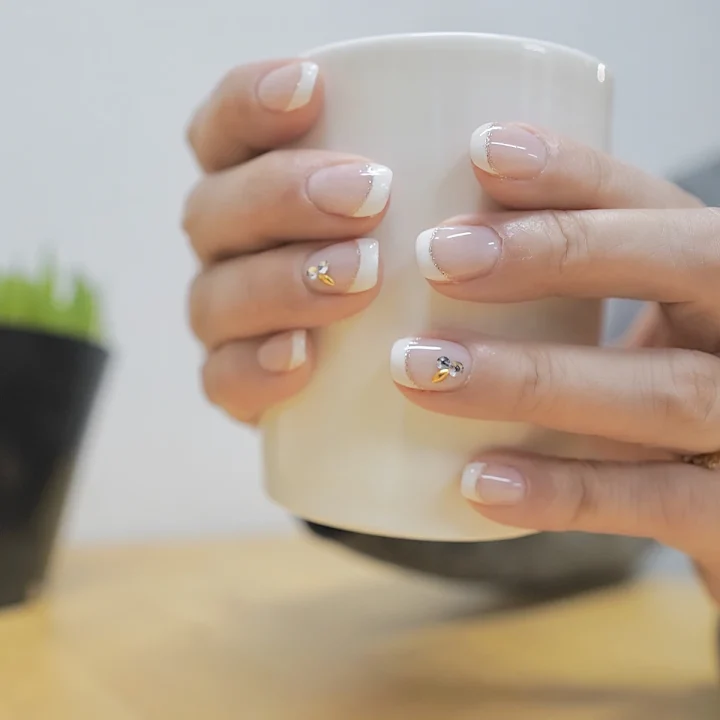French blanche sur ongles courts autour d’une tasse
