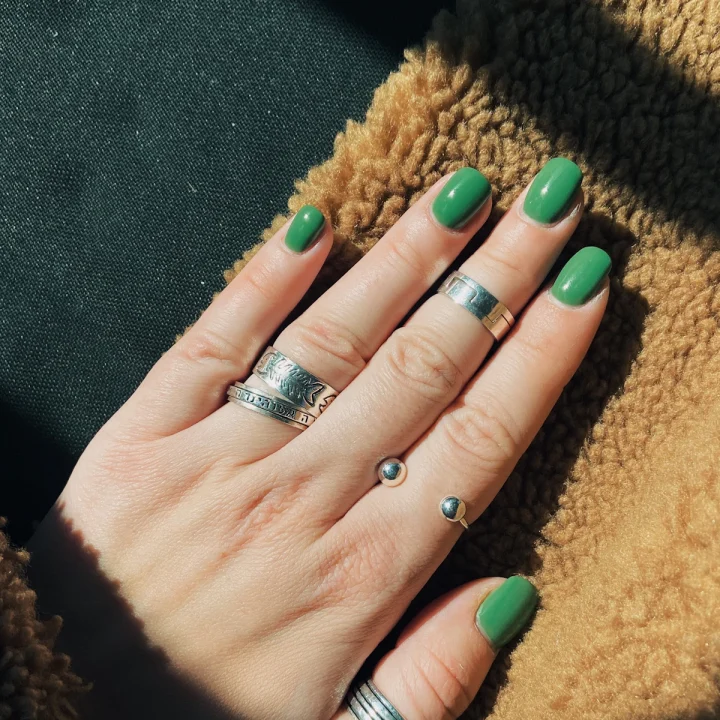 Ongles courts vert vif et bagues argentées
