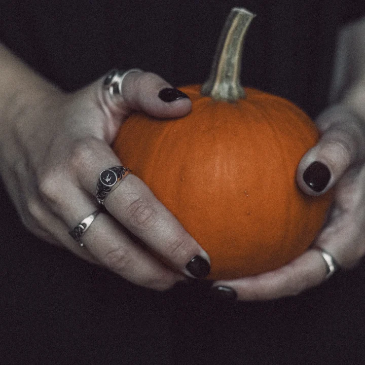 Ongles prune foncé autour d’une citrouille
